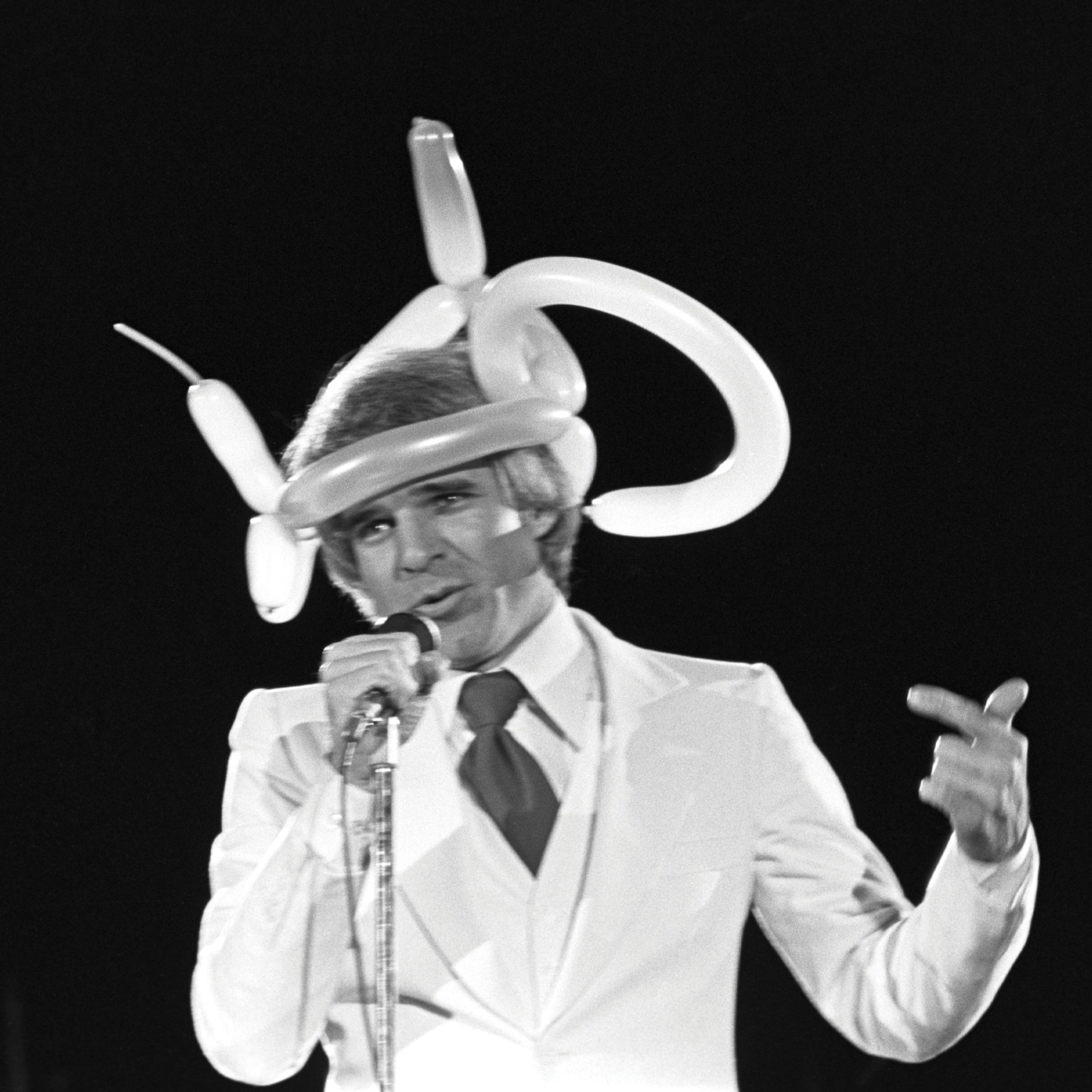 A black and white photo of a comedian wearing a balloon hat.