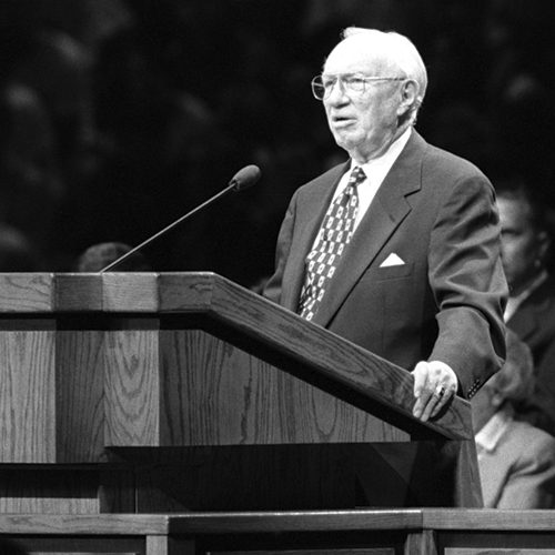A black and white photo of Gordon B. Hinckley speaking at a podium in 1995.