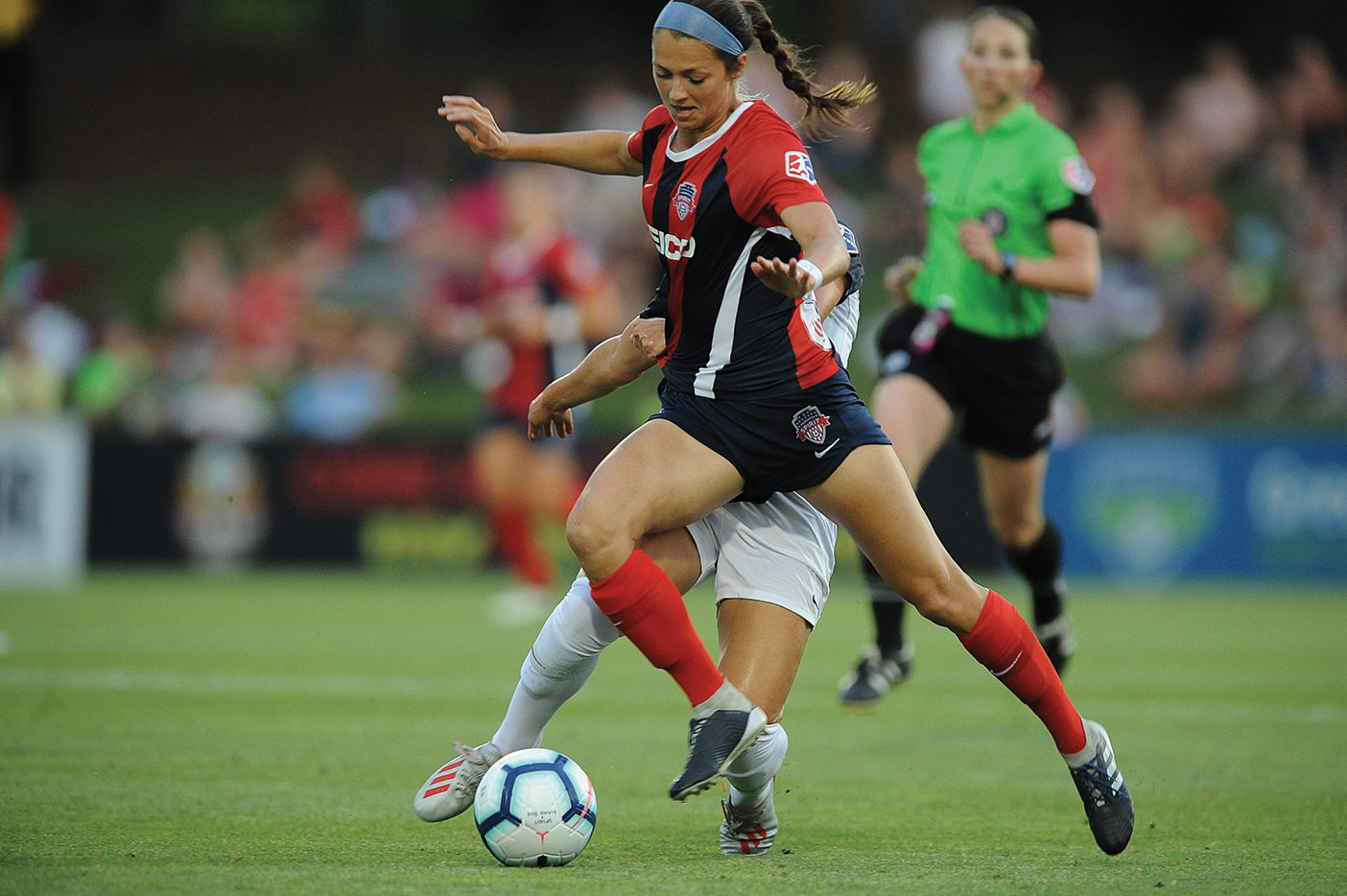 Ashley Hatch faces off against another player in a soccer game.