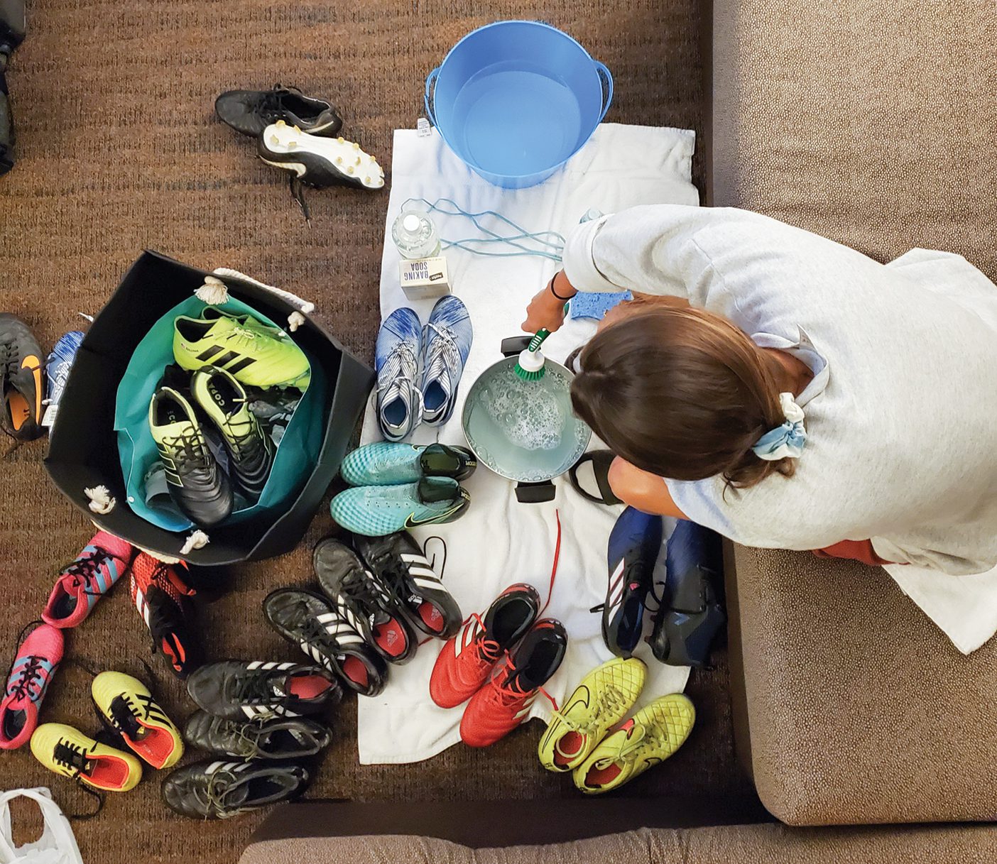 A woman cleans a bunch of brightly colored cleats.