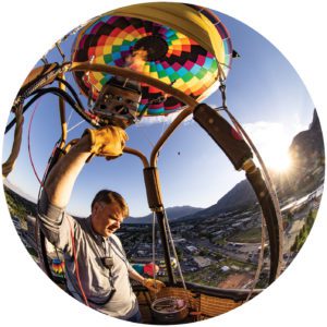 A photo taken with a fish eye lens shows a man in a hot-air balloon.