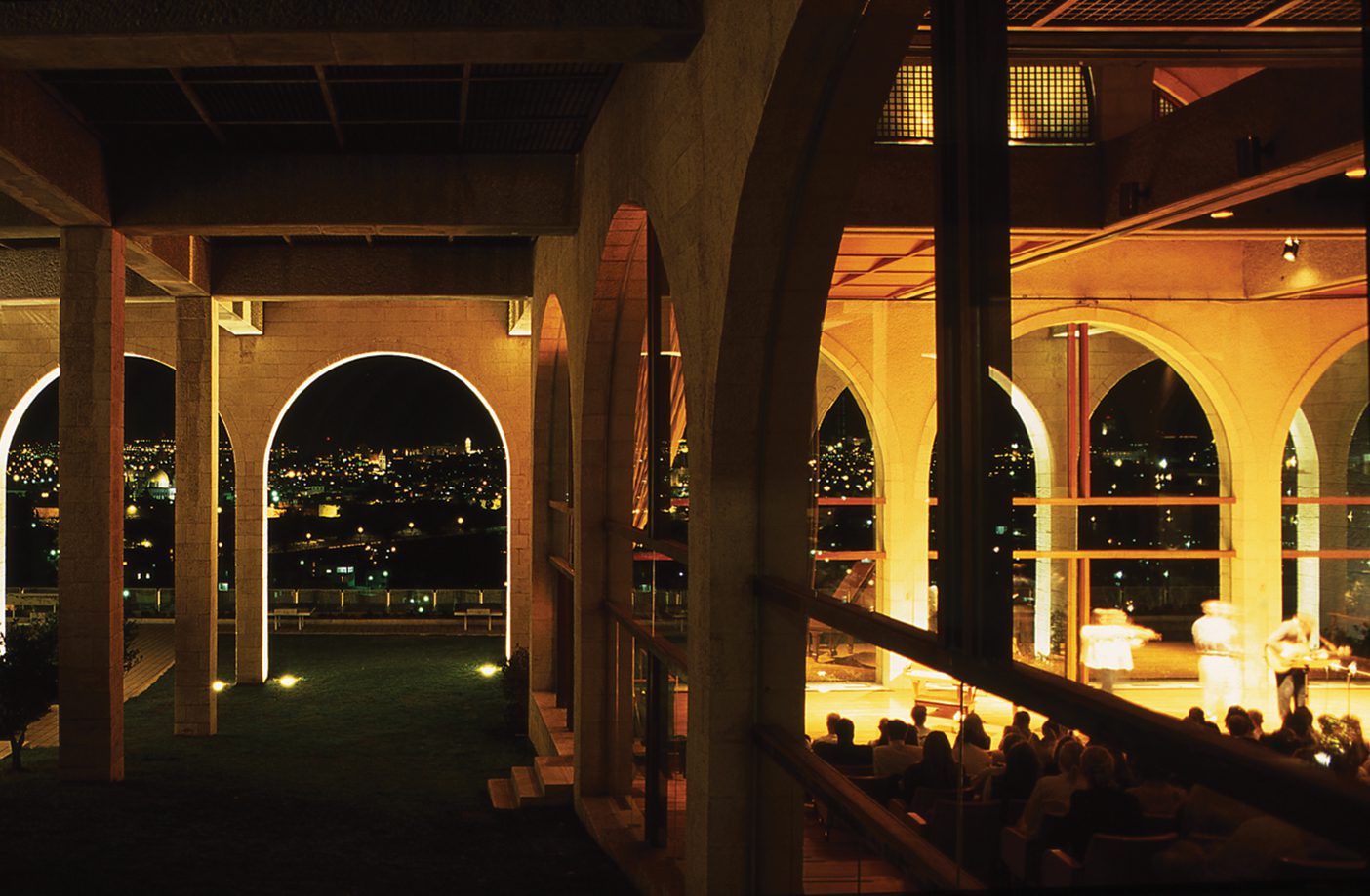 A photo inside the BYU Jerusalem Center. There are big windows showing a night view of the city.