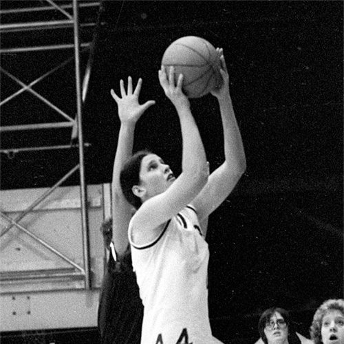 A black and white photo of a female athlete paring to shoot a basketball.