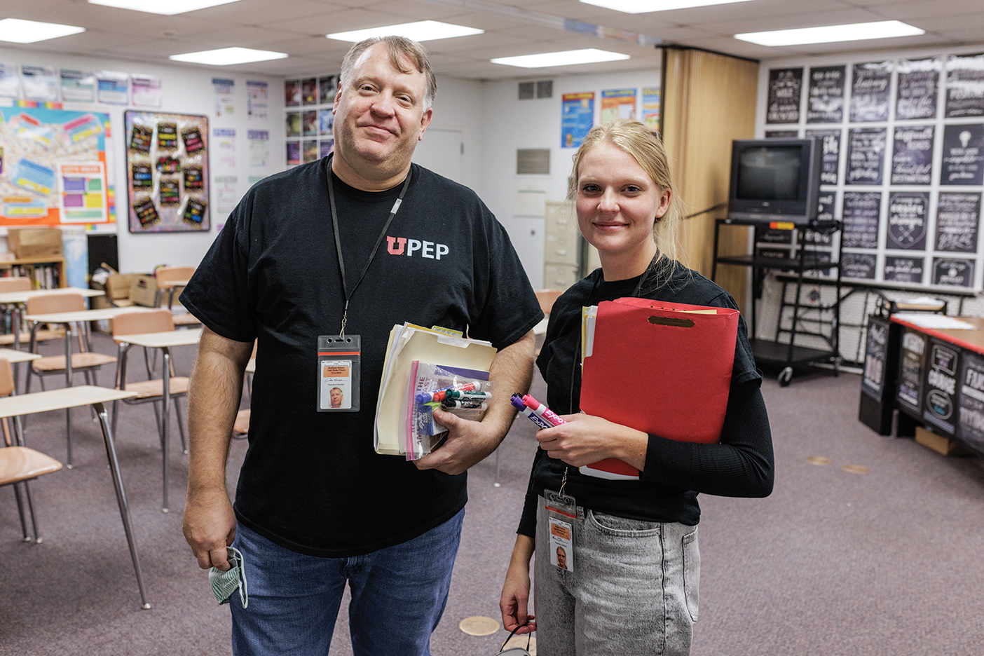 A professor and his teaching assistant hold class materials at the front of a prison classroom.