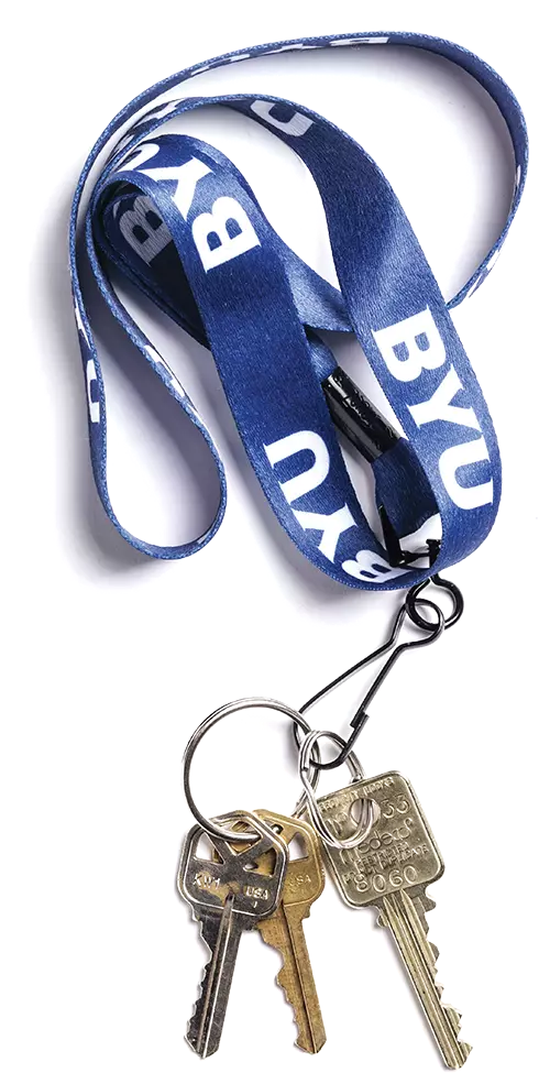 A blue lanyard with the BYU logo and a set of keys to a student apartment