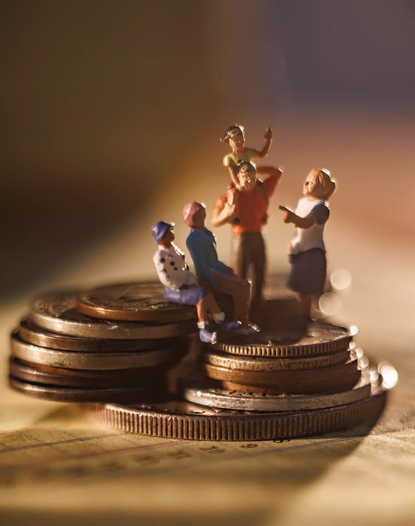 A happy figurine family stands atop a pile of coins.