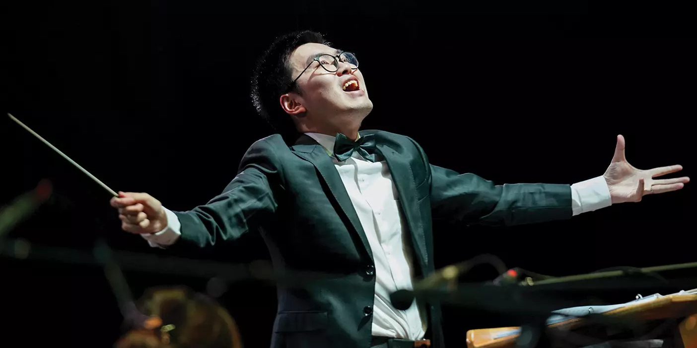 A Chinese man conducts a choir with much gusto and passion.