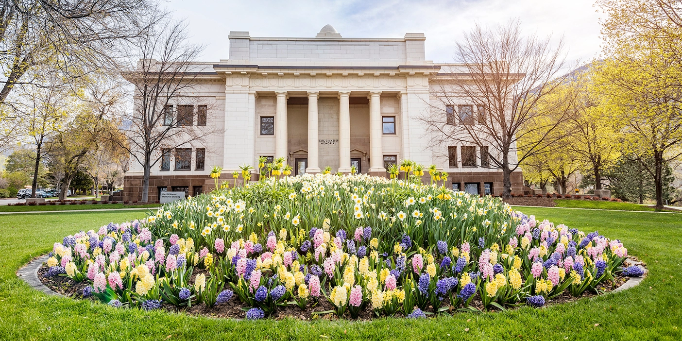 The Maeser Building on BYU campus with a flowerbed in the foreground.