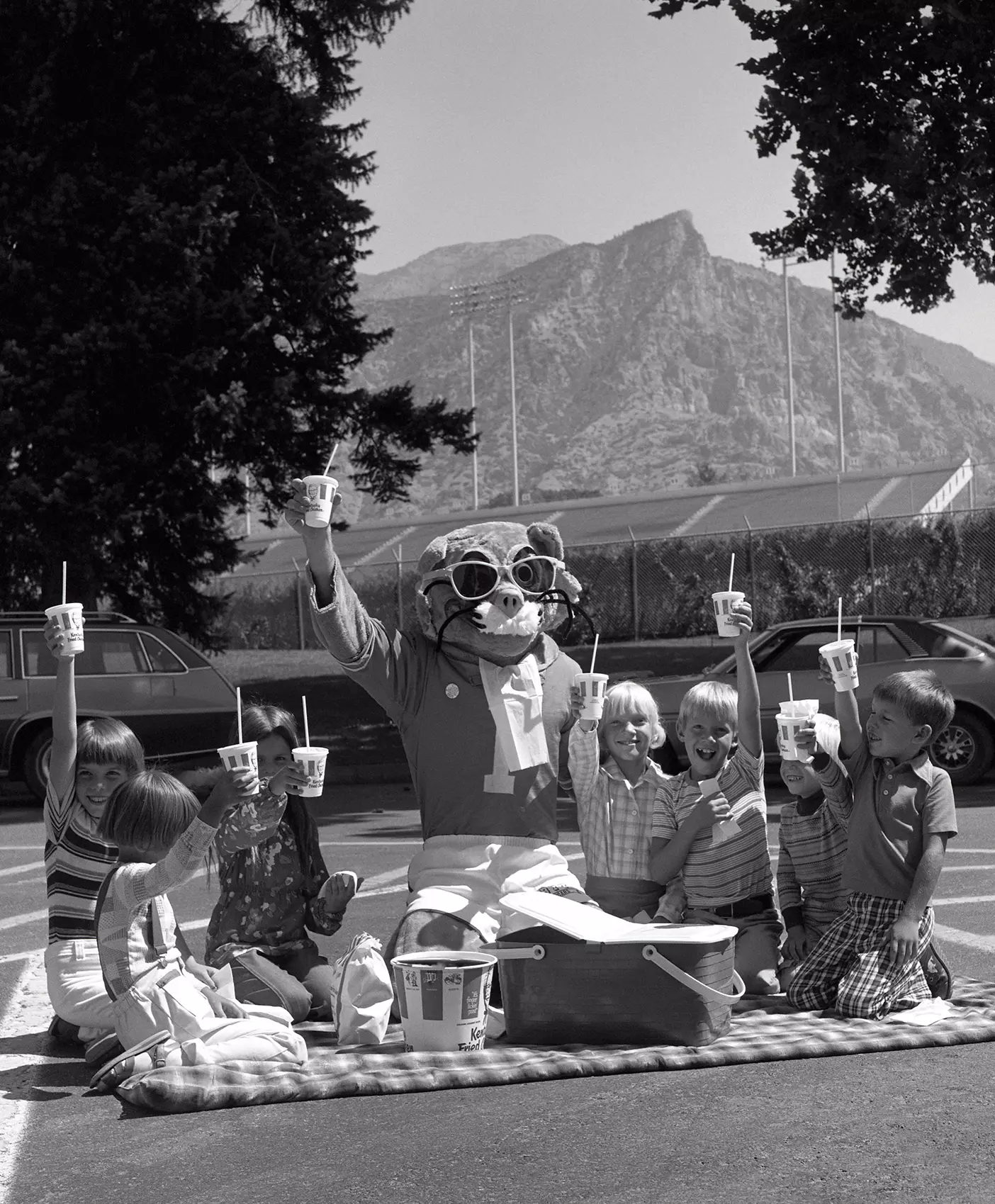 BYU mascot Cosmo the Cougar enjoys a lunch with young friends in 1977.