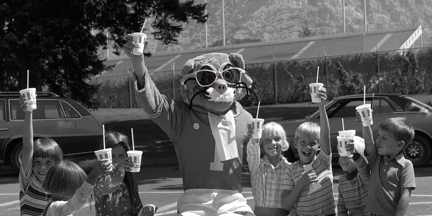 BYU mascot Cosmo the Cougar enjoys a lunch with young friends in 1977.