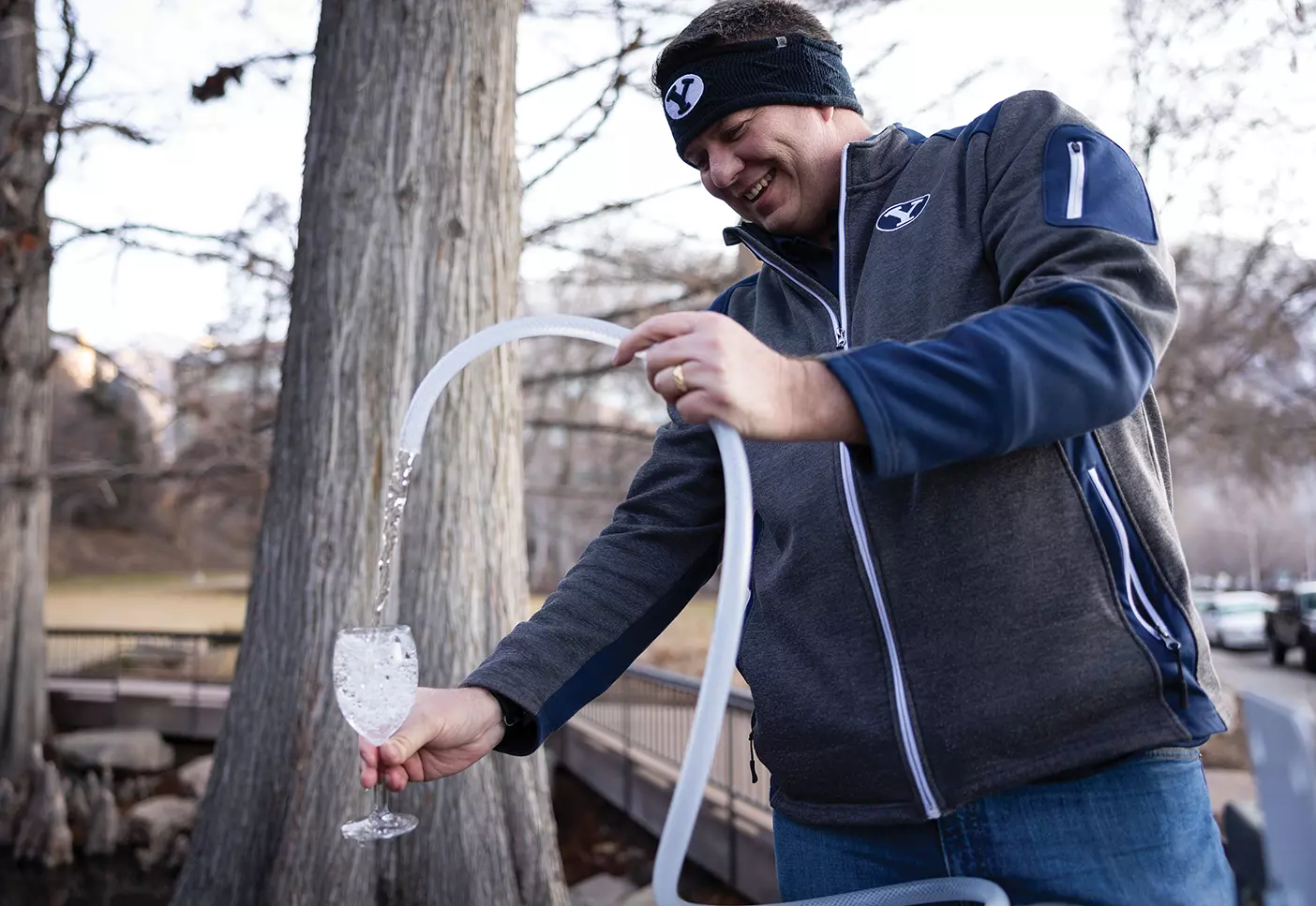A smiling man pours water from the duck pond into a cup