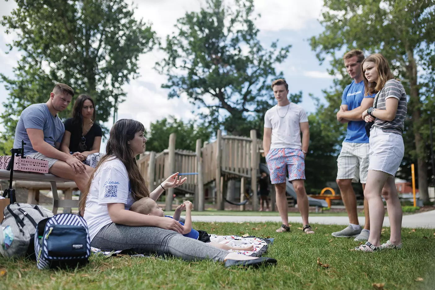 Brittany Markham holds her baby, Damian, as she talks with friends at a Provo park.