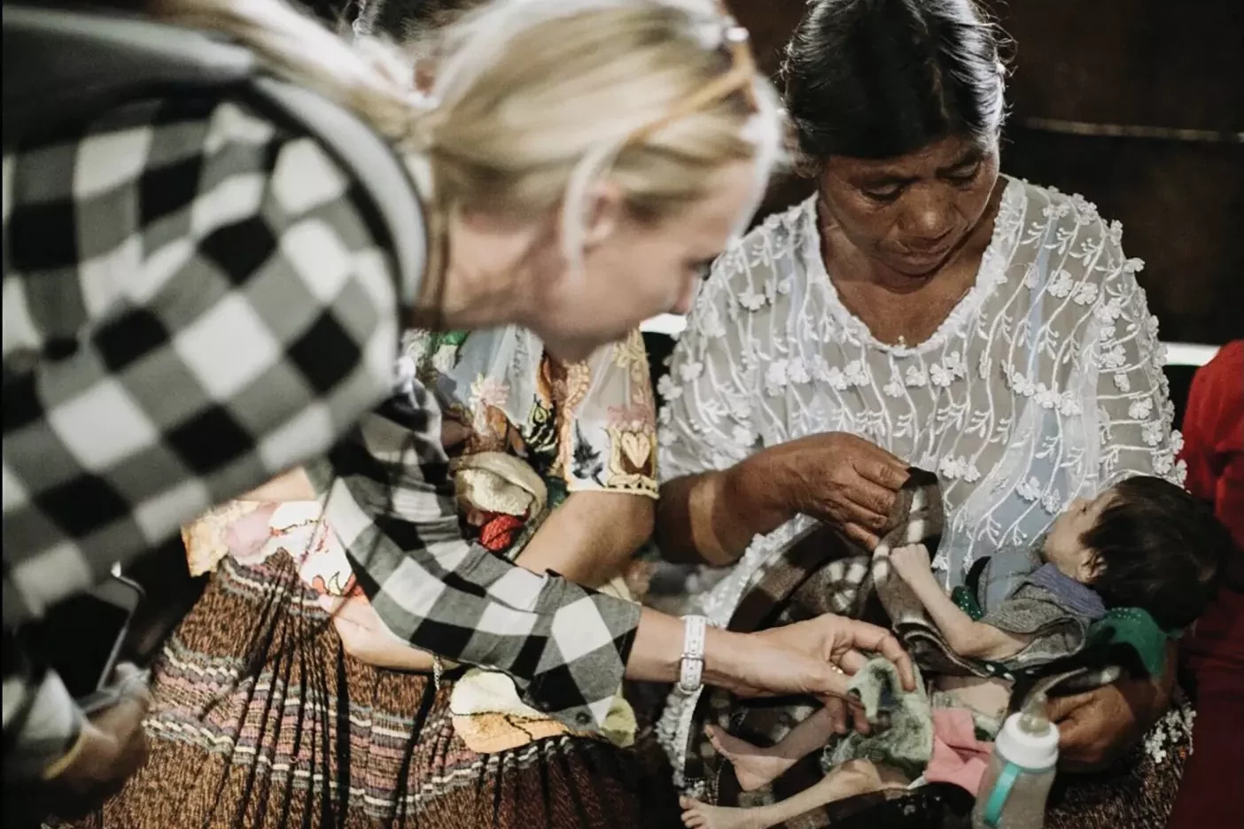 A woman helps a mother and baby in Guatemala.