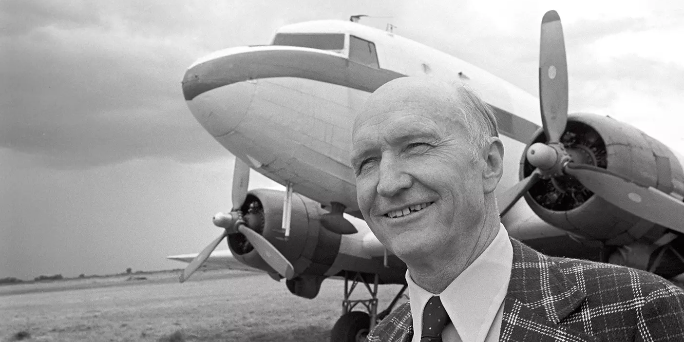 Gail Halvorsen on the runway, smiling and standing in front of an aircraft.