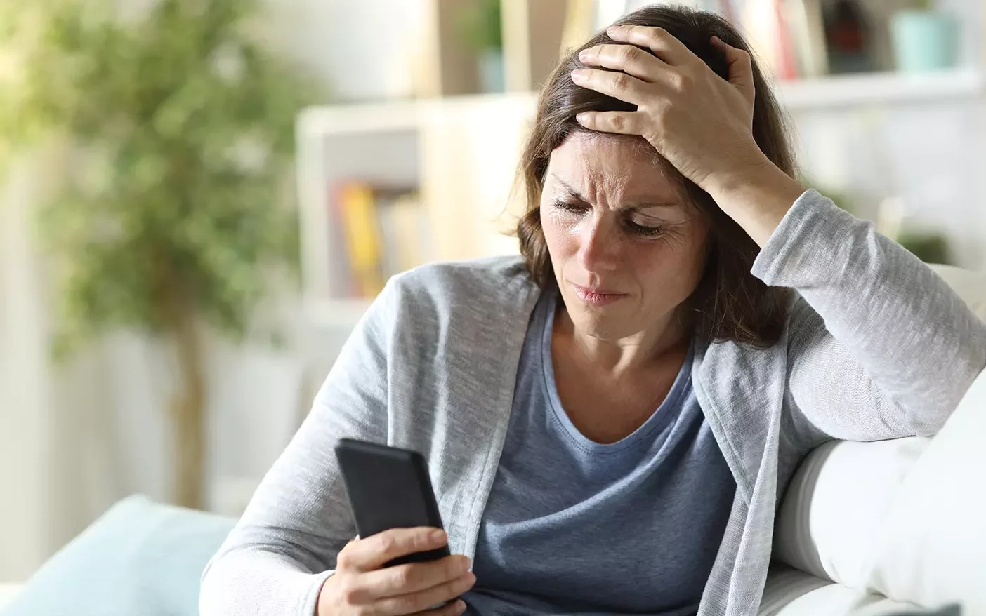 A distressed woman looks down at a cell phone.