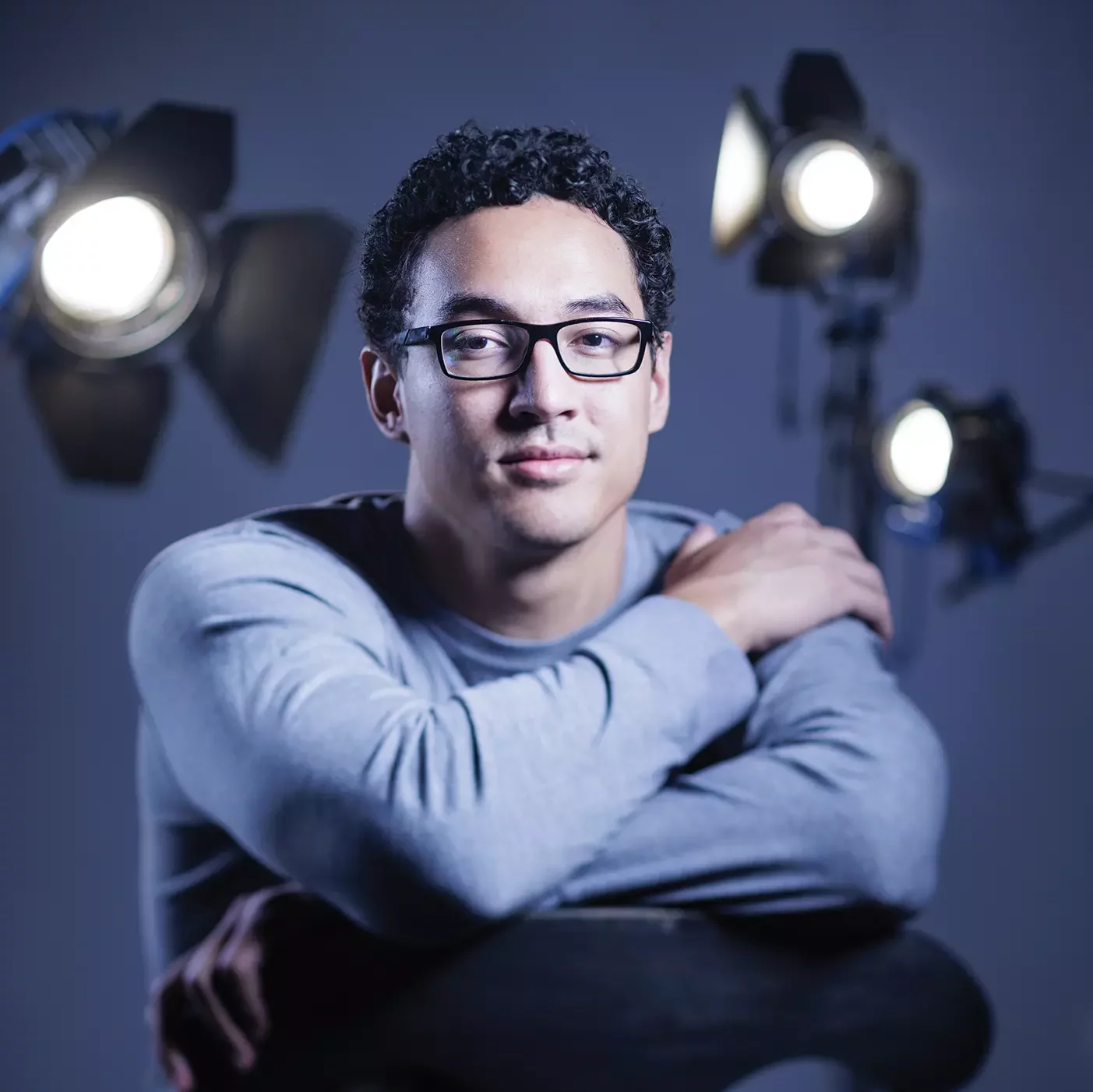 Langi Tuifua poses on a film set with lights in the background.