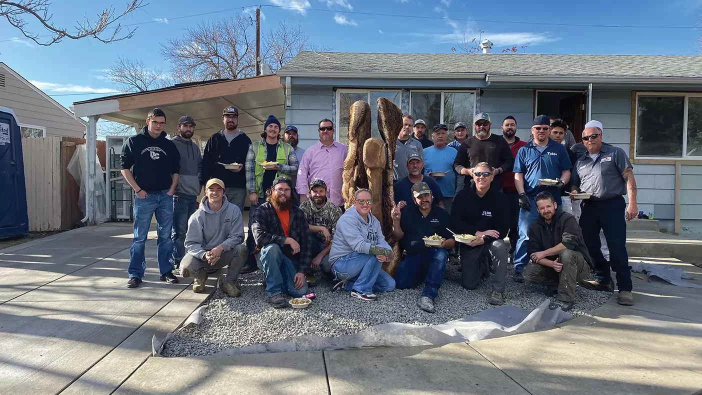 A group of volunteer construction workers stand outside a home that's gone through a makeover.