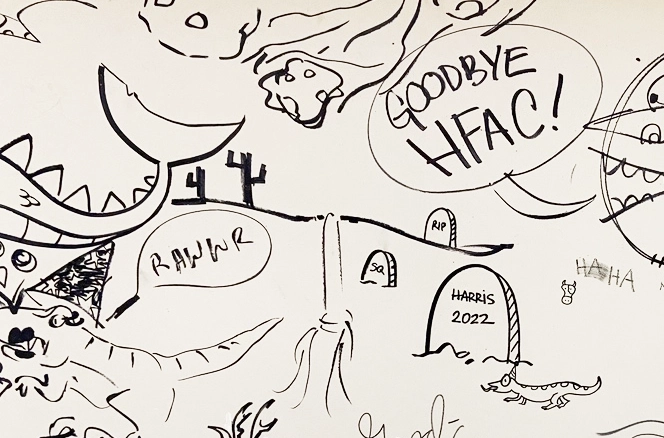 Cartoon art on a wall in the Harris Fine Arts Center, before its demolition. The art includes a T-Rex, meteors, a tombstone with "Harris 2022," and the words "Goodbye, HFAC."