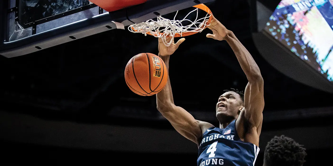 A BYU basketball player jumps high above his competition and team to dunk the basket