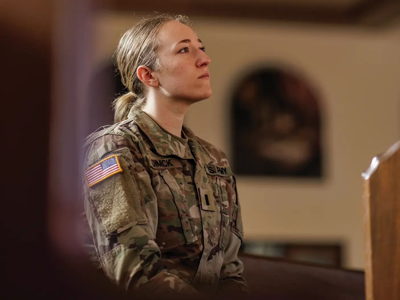 A female military chaplain ponders while in a church.