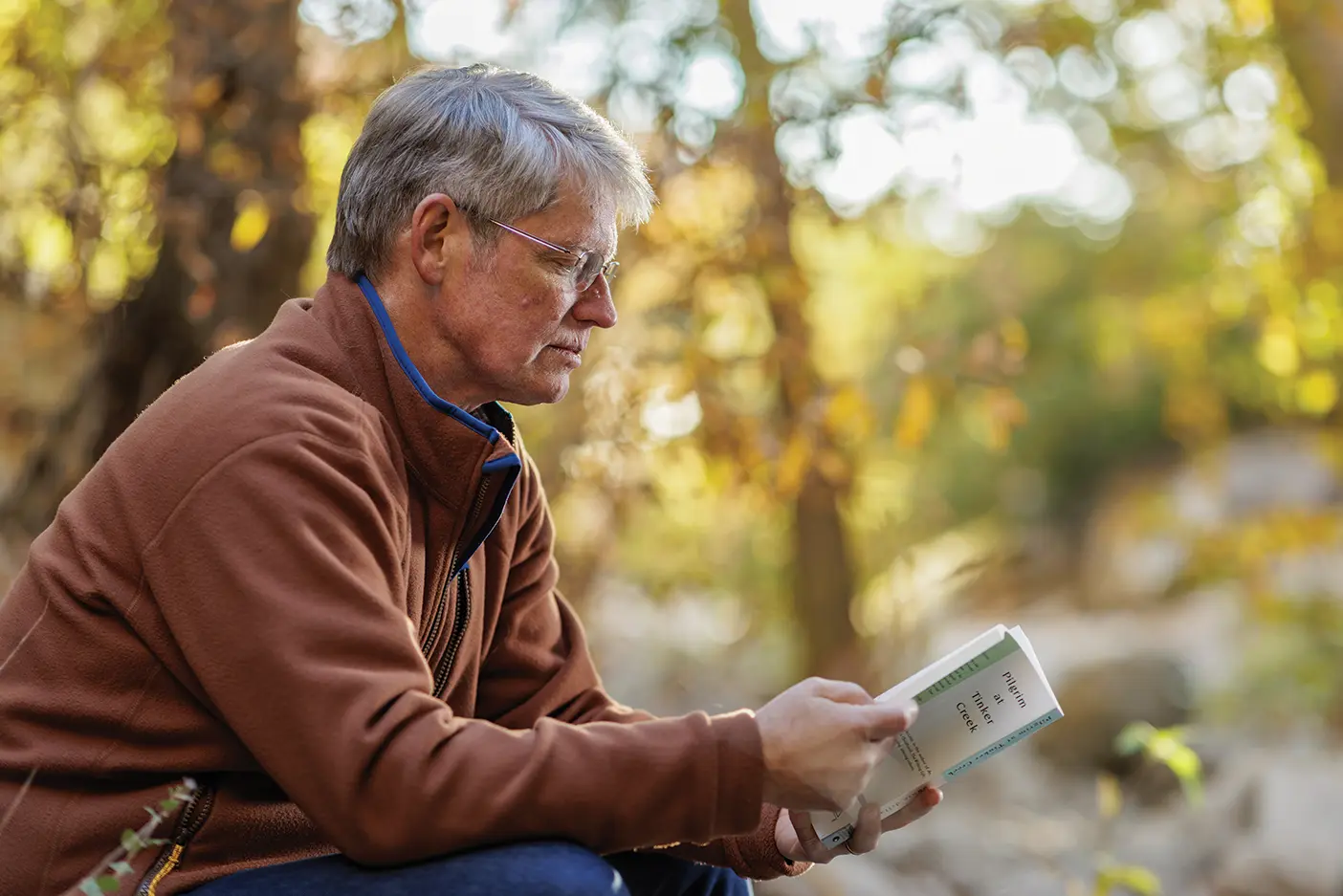 A man contemplates as he reads a book in nature