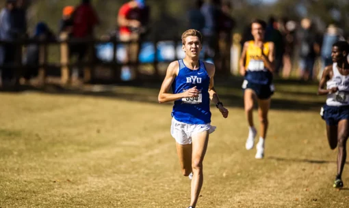 Distance runner Casey A. Clinger ('23) runs down a grassy field, leading the pack.
