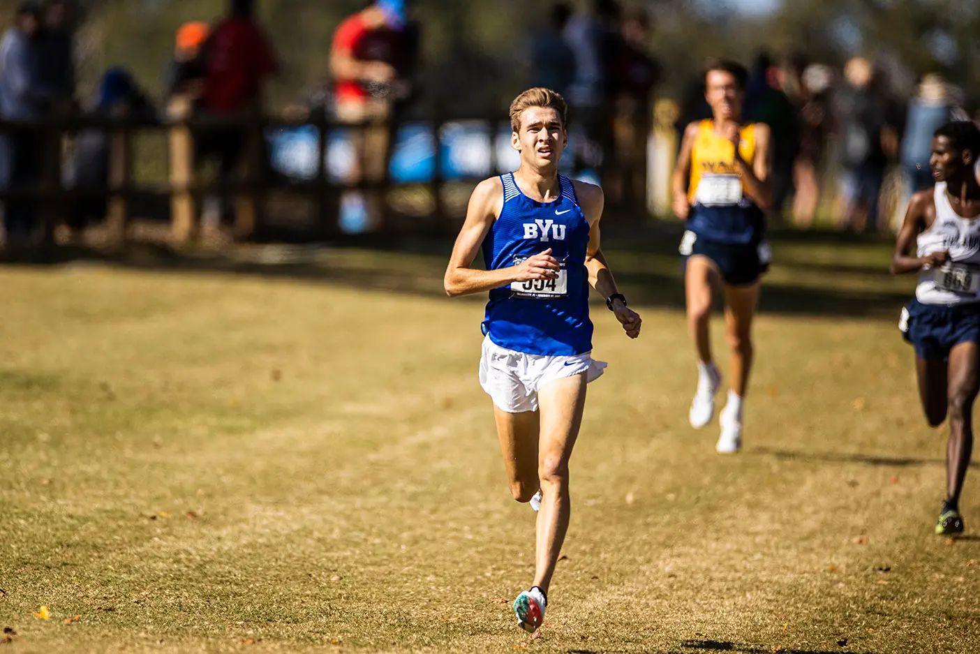 Distance runner Casey A. Clinger ('23) runs down a grassy field, leading the pack.