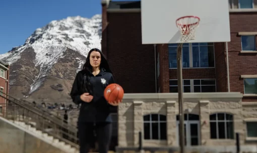 Lauren Gustin poses with a basketball in one hand on an outdoor court.