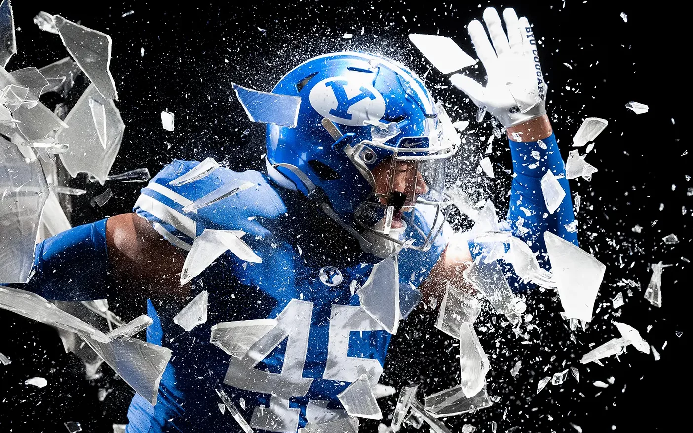 BYU football player busts through a sheet of sugar glass.