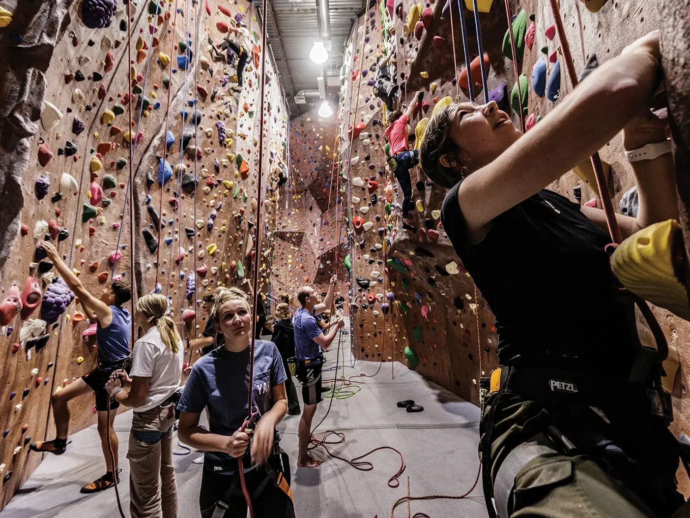 A BYU student looks up at the rock climbing wall in an indoor venue