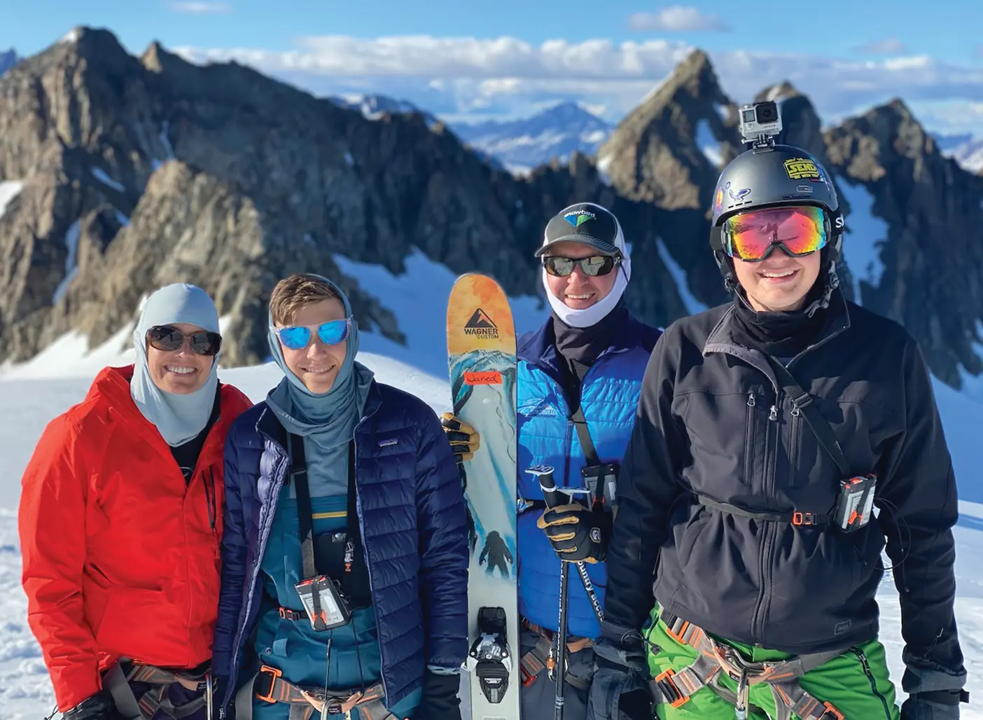 Nielsen and her family stand on a sunny mountain top in colorful ski clothing, all wearing highly reflective sunglasses.