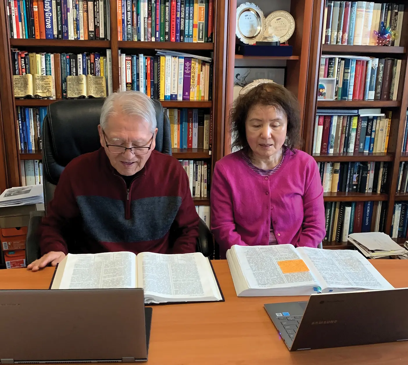 Spencer Shin and Chi Hyo Sun sitting at a desk in a library, studying the scriptures.