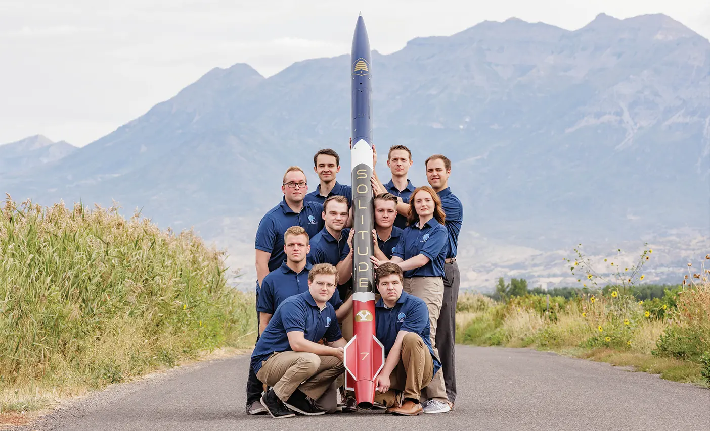 BYU engineering students stand around a rocket they designed