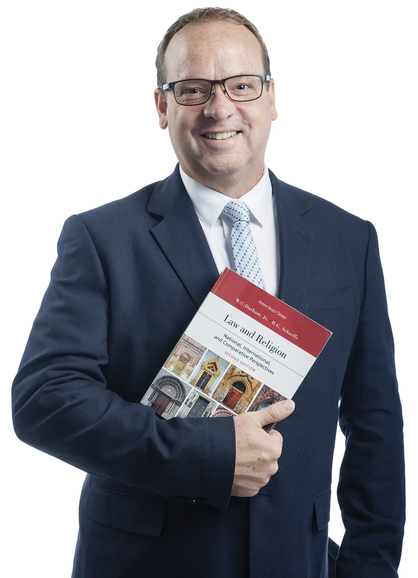 A male law professor in a suit and tie holds a textbook about law and religious liberty