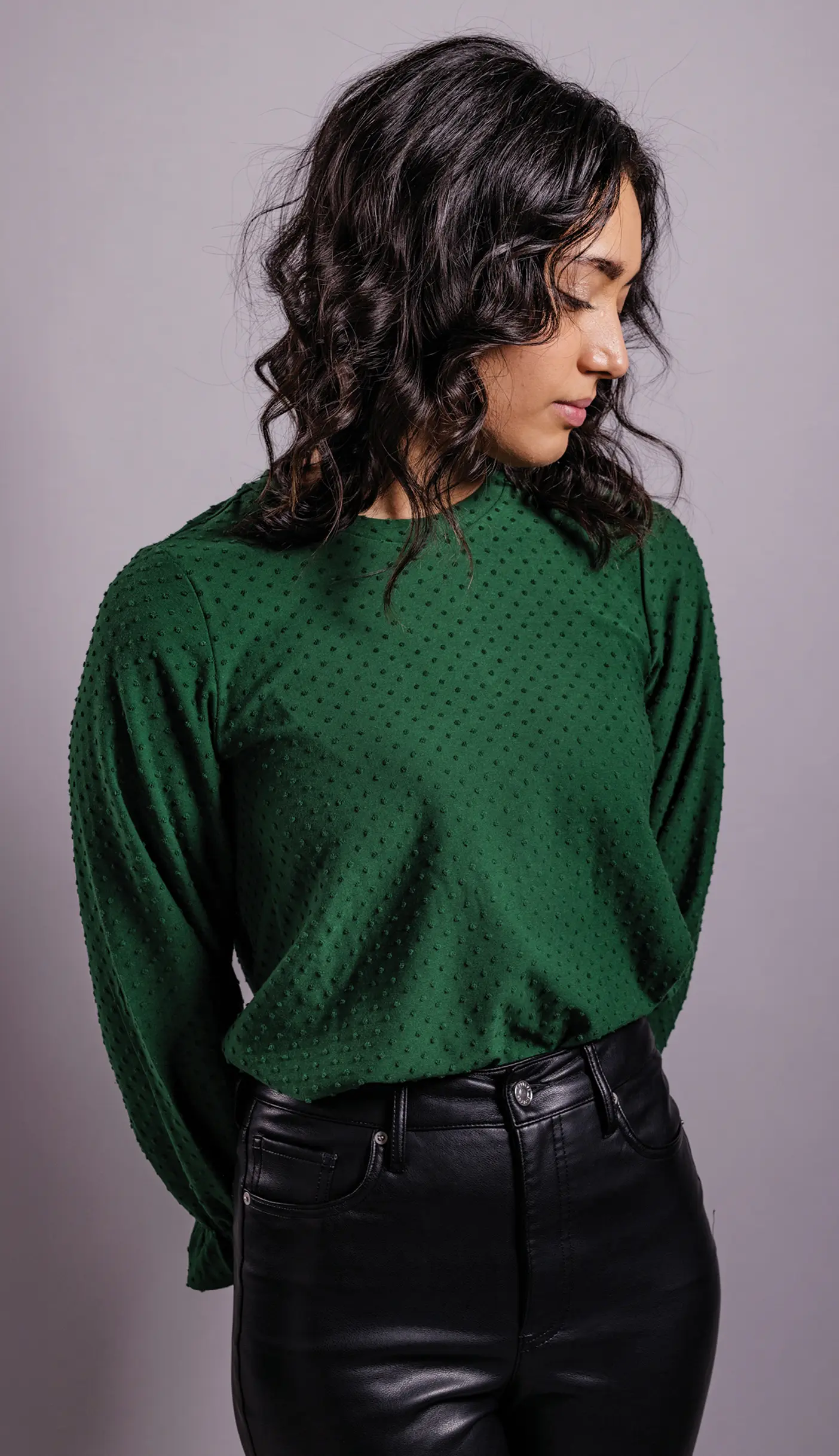 A woman in a green sweater poses