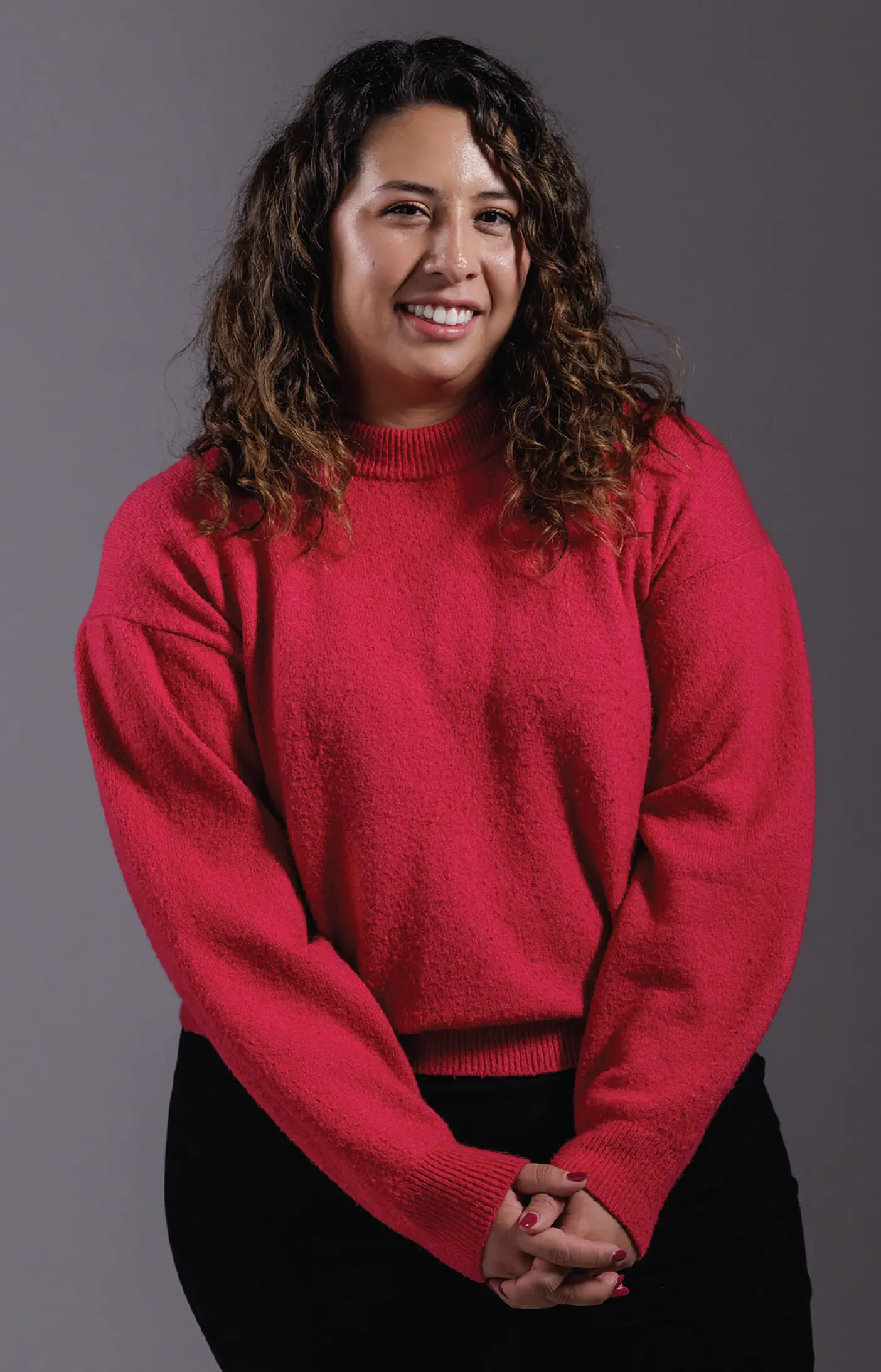A woman poses in a red sweater