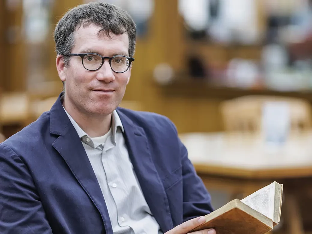 Religion professor Joseph Spencer holds an old copy of the Book of Mormon in BYU's Special Collections.
