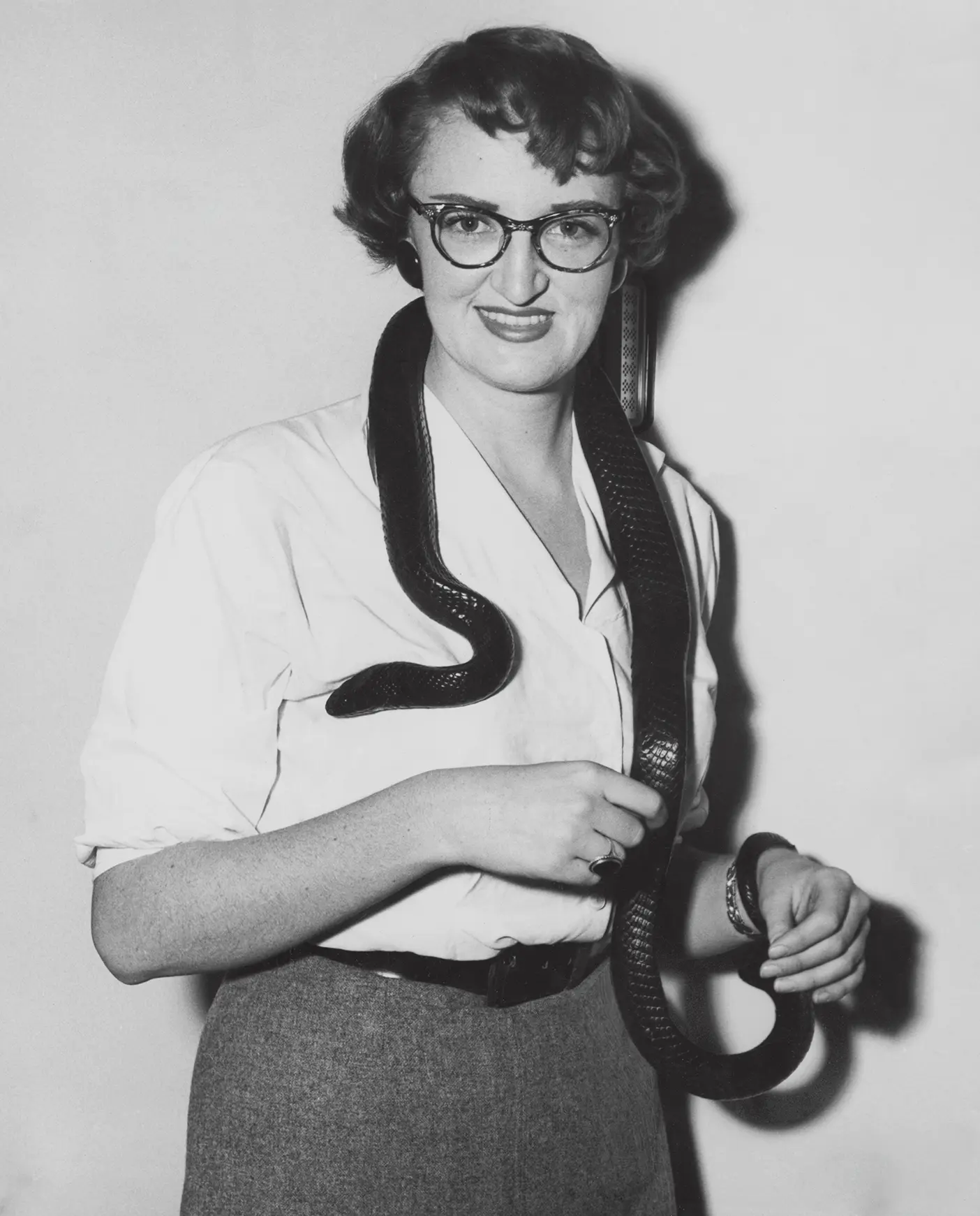 Black and white photo of a woman holding a snake around her neck.
