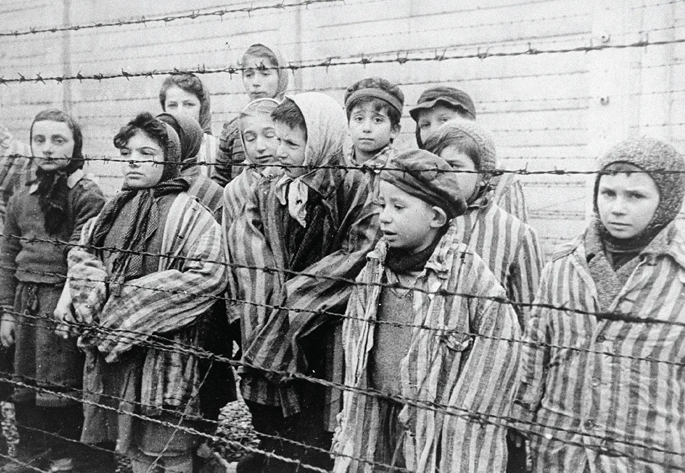 Children stand behind barbed wire in Auschwitz in 1945.