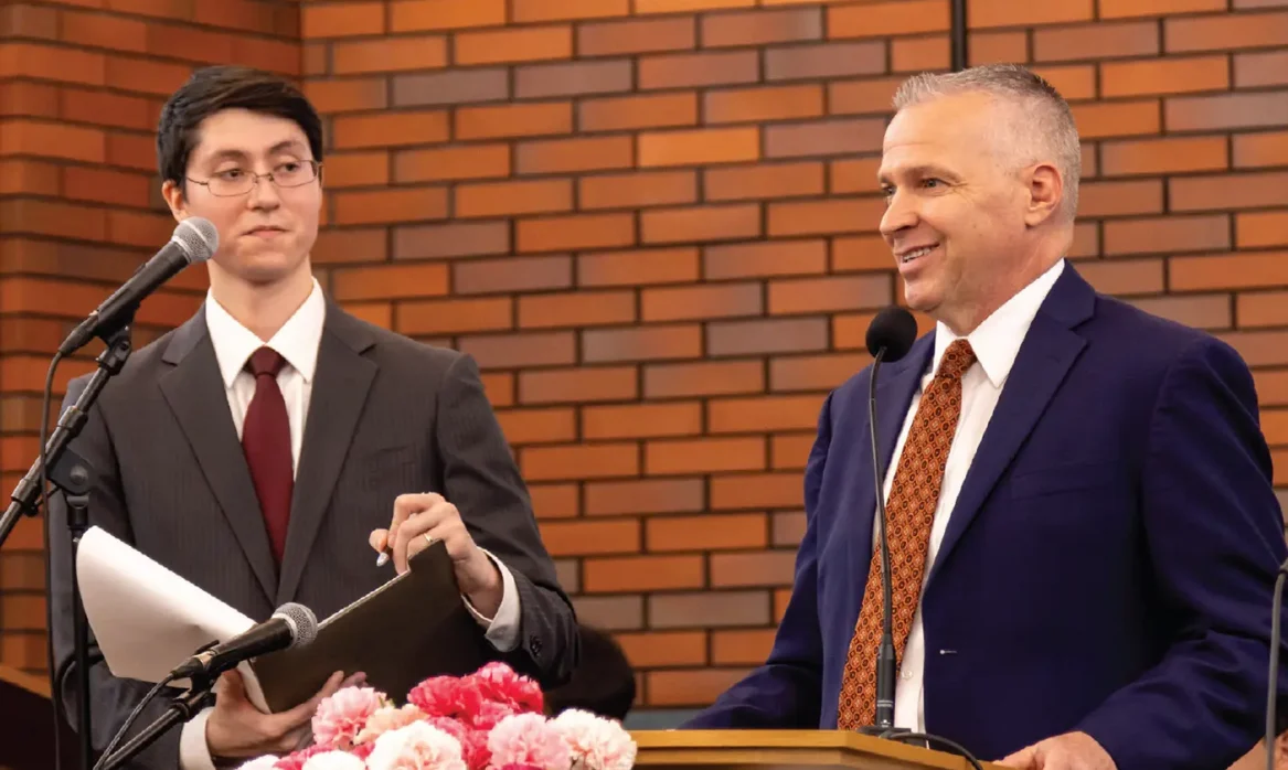 A man in a suit with a red tie stand at a podium at a LDS church building in Tokyo, Japan.