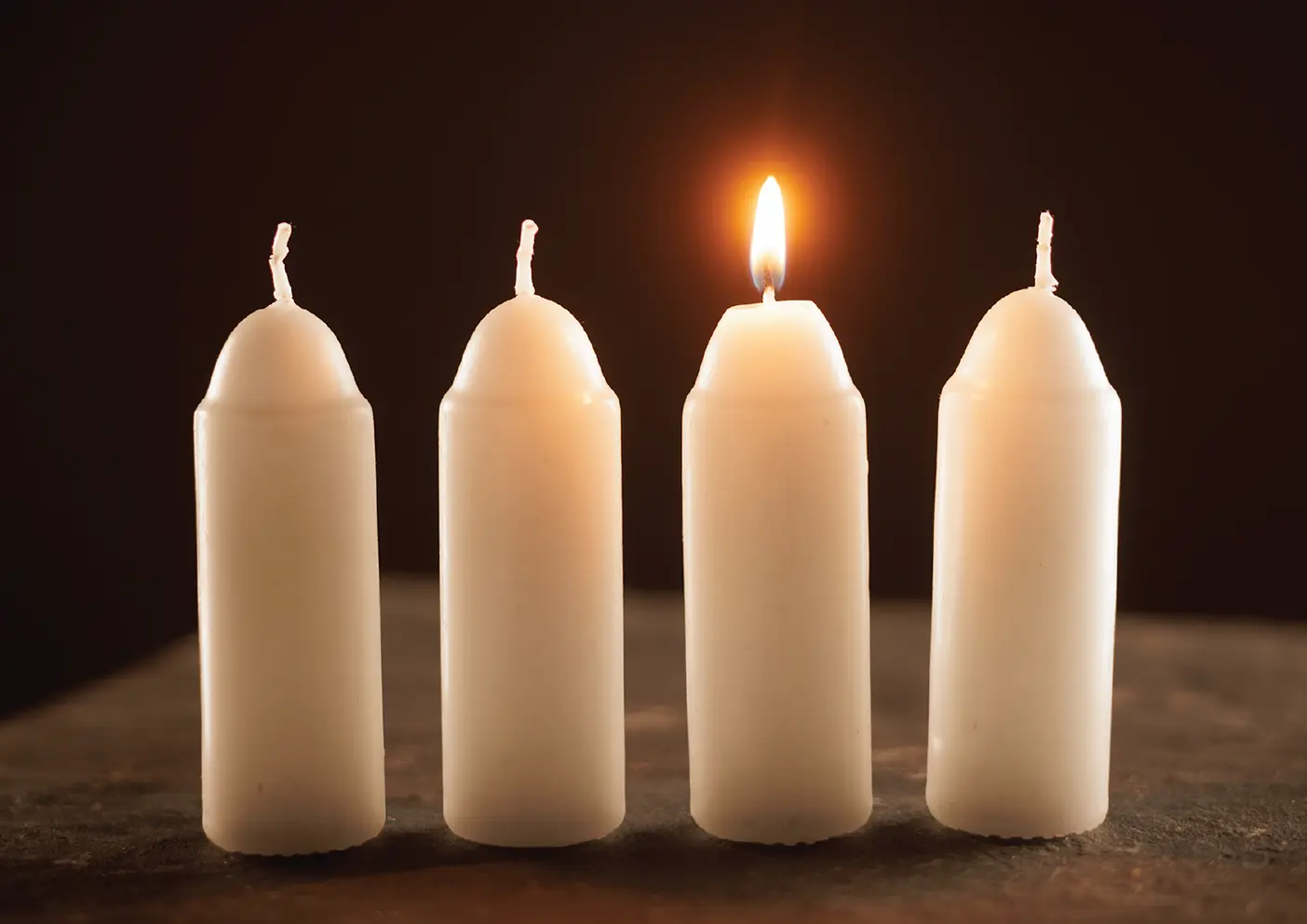 Four candles with one lit.