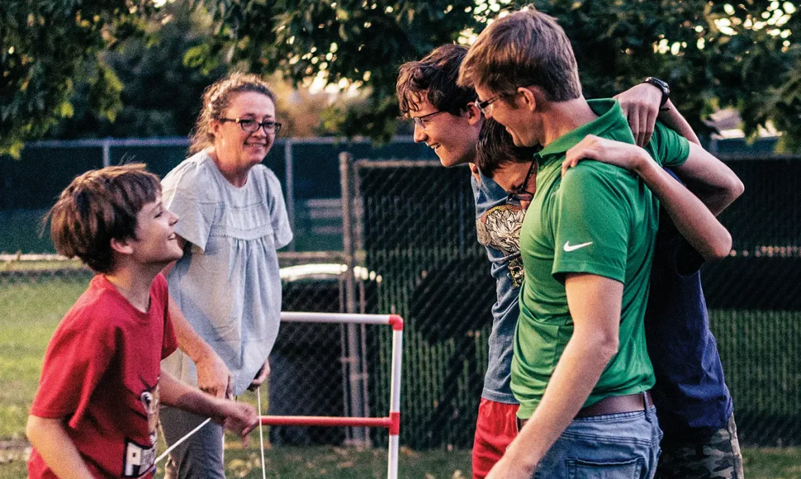 A smiling family plays an outdoor game together.