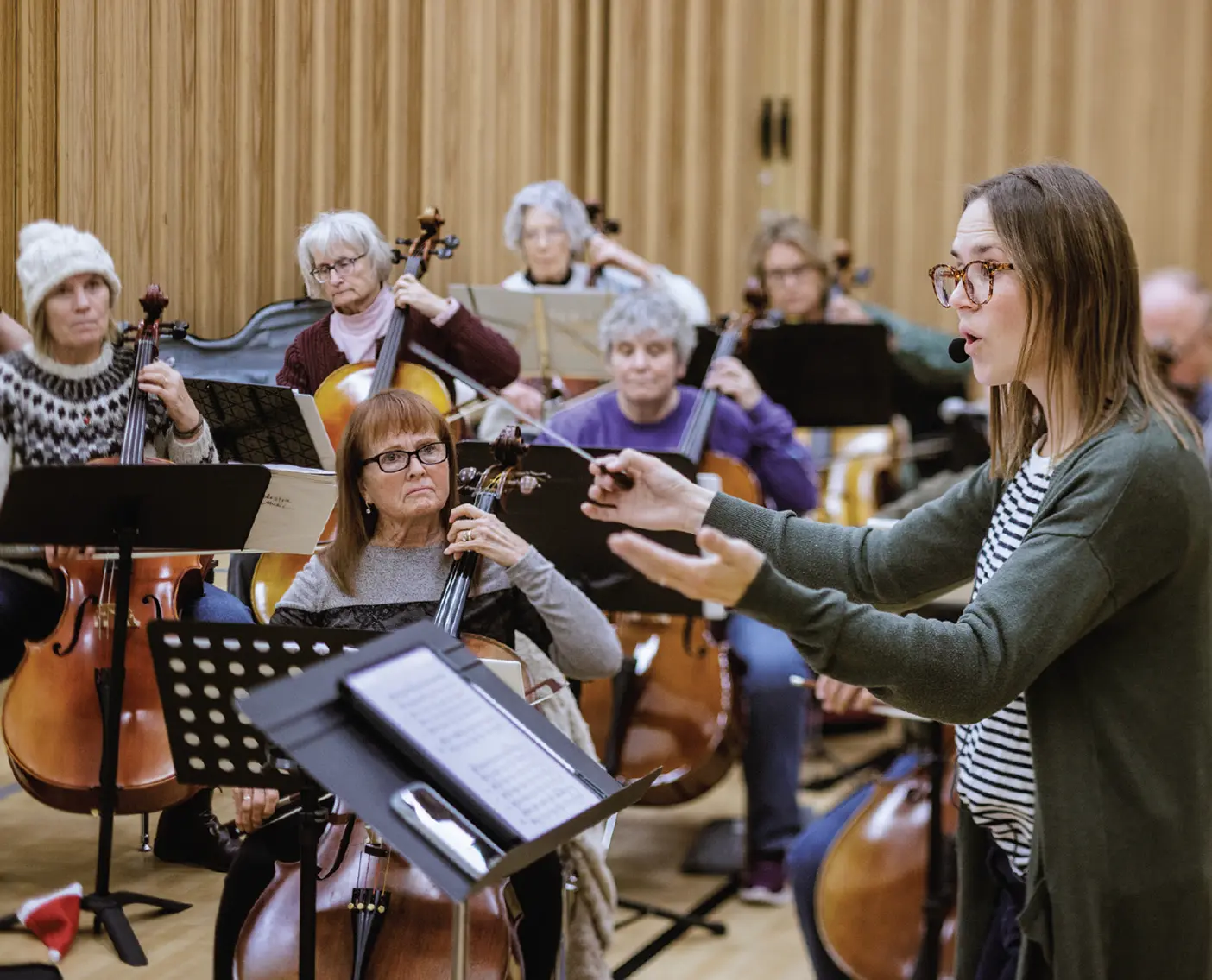 A woman conducts a string orchestra made up of older adults