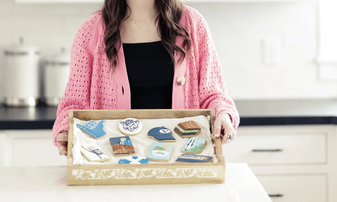 Anya holds a platter of Anya's Cookies with custom BYU designs.