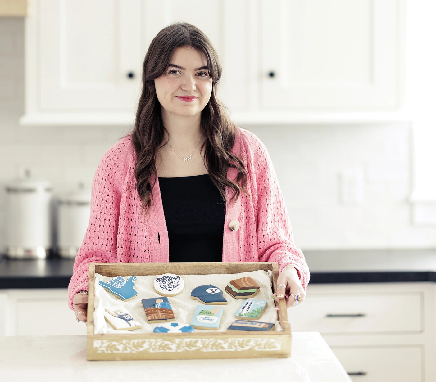 Anya holds a platter of Anya's Cookies with custom BYU designs.