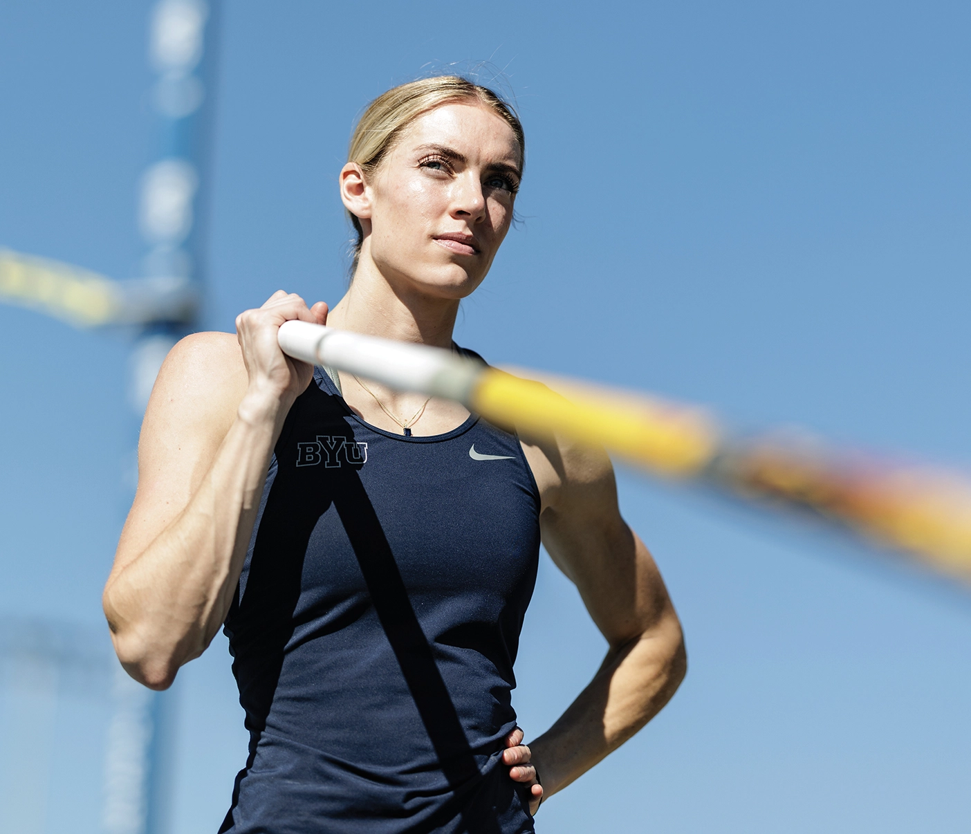 Maren poses with her hand on her hip and a vaulting pole over her shoulder.
