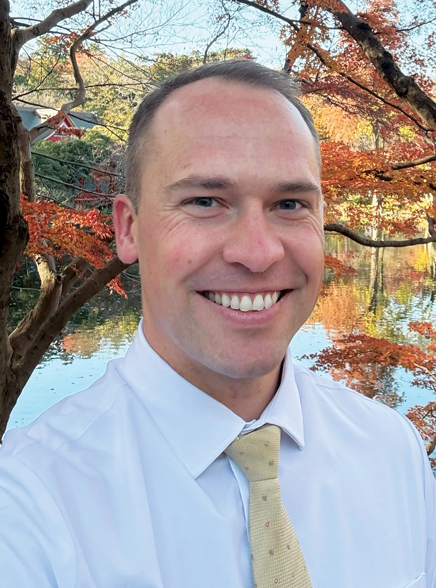 Spencer poses in front of a pond in autumn.