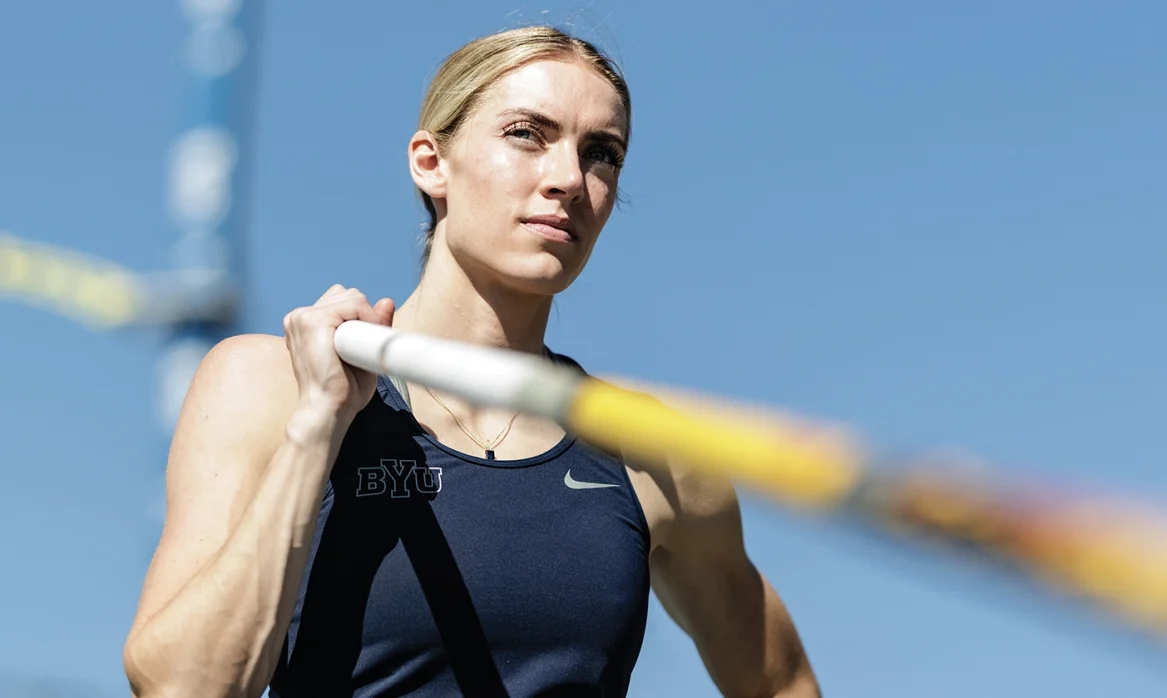 Maren poses with her hand on her hip and a vaulting pole over her shoulder.