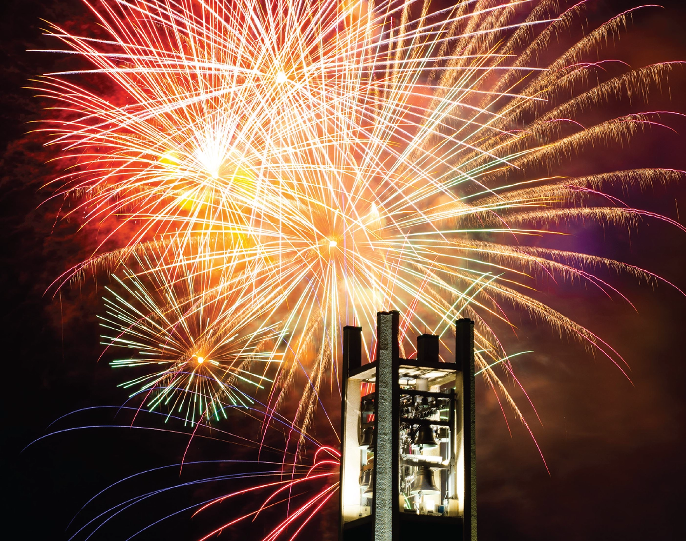 The BYU Bell Tower in front of a firework-lit sky