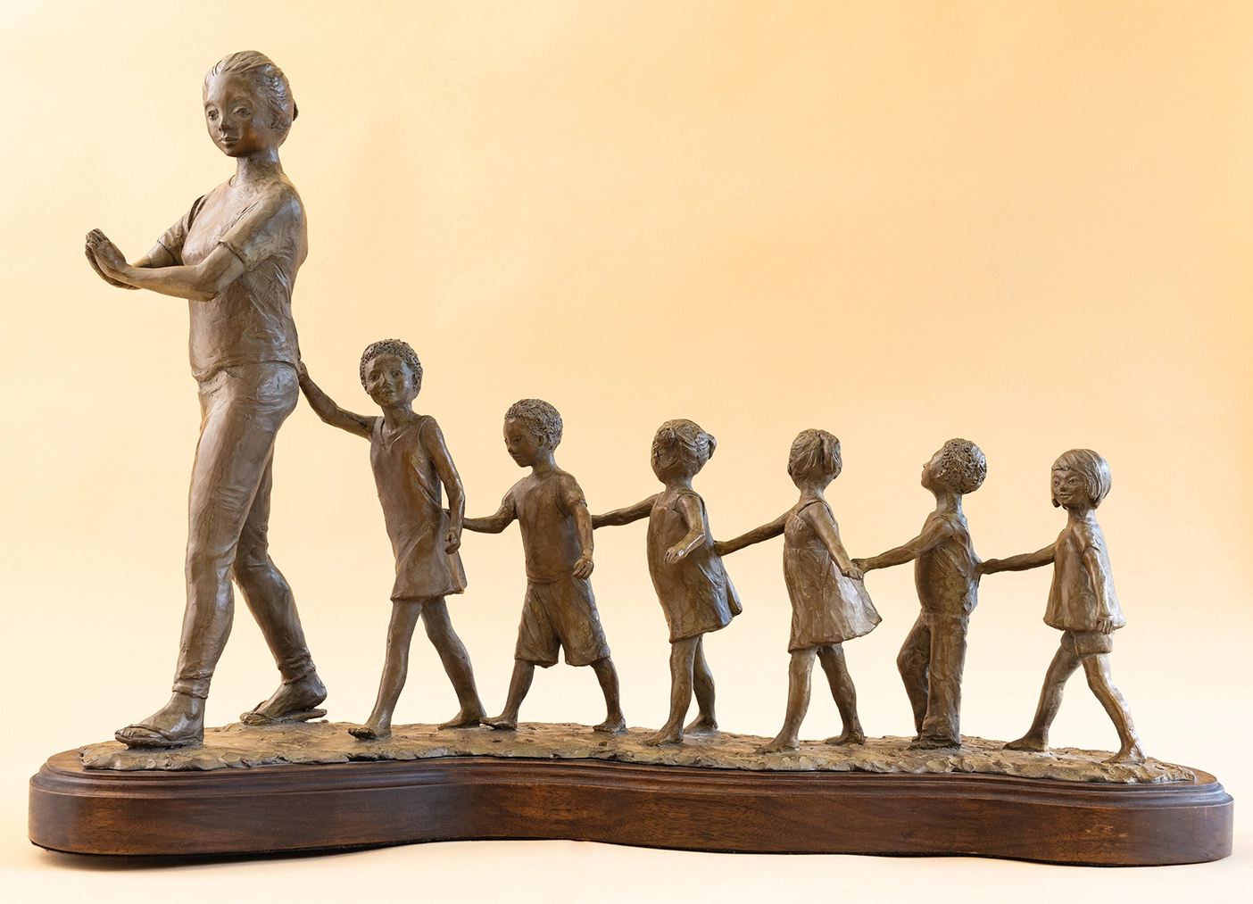 A sculpture depicting an adult figure leading six children. 